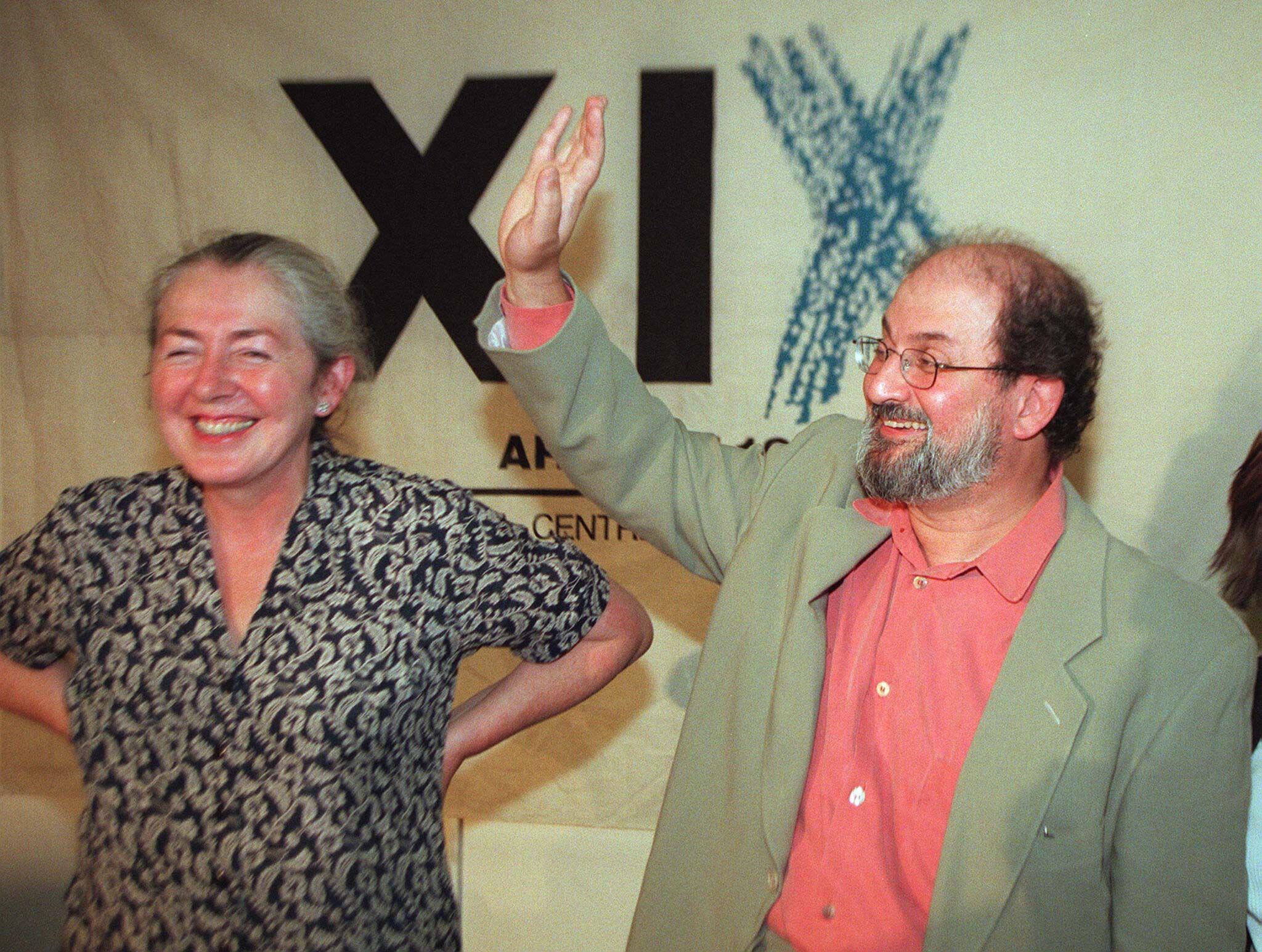 Salman Rushdie and ARTICLE 19's Carmel Bedford smiling in front of an ARTICLE 19 banner 