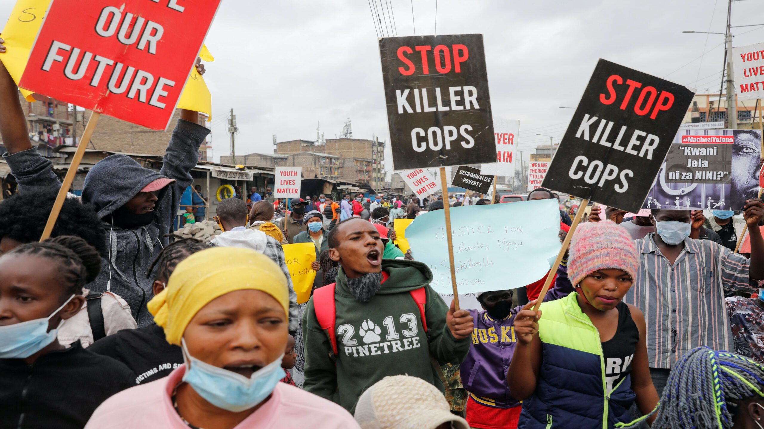 Group of people at a street protest holding signs that say 'Stop Killer Cops'. 