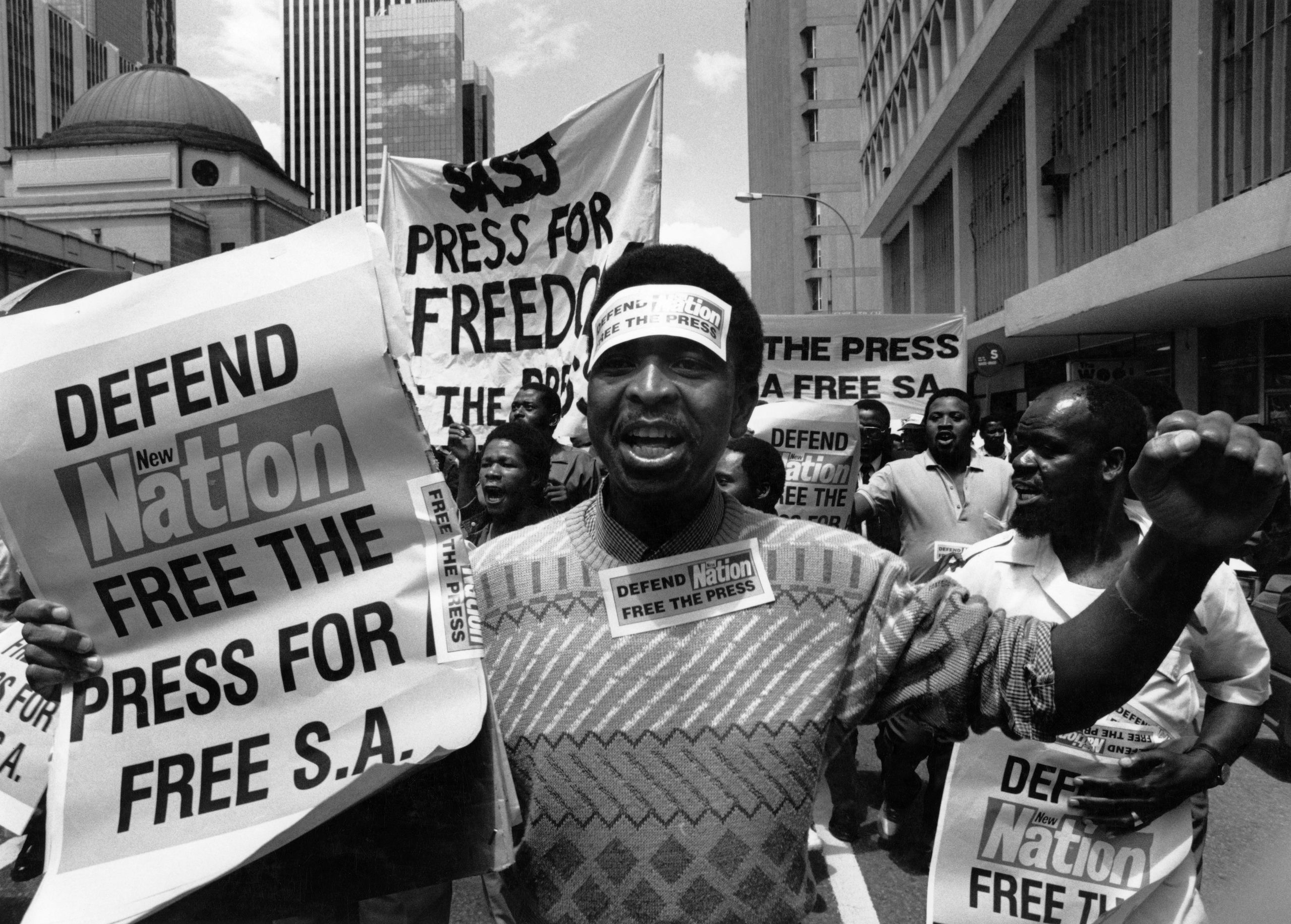 A group of people at a protest march holding banners calling for press freedom in South Africa