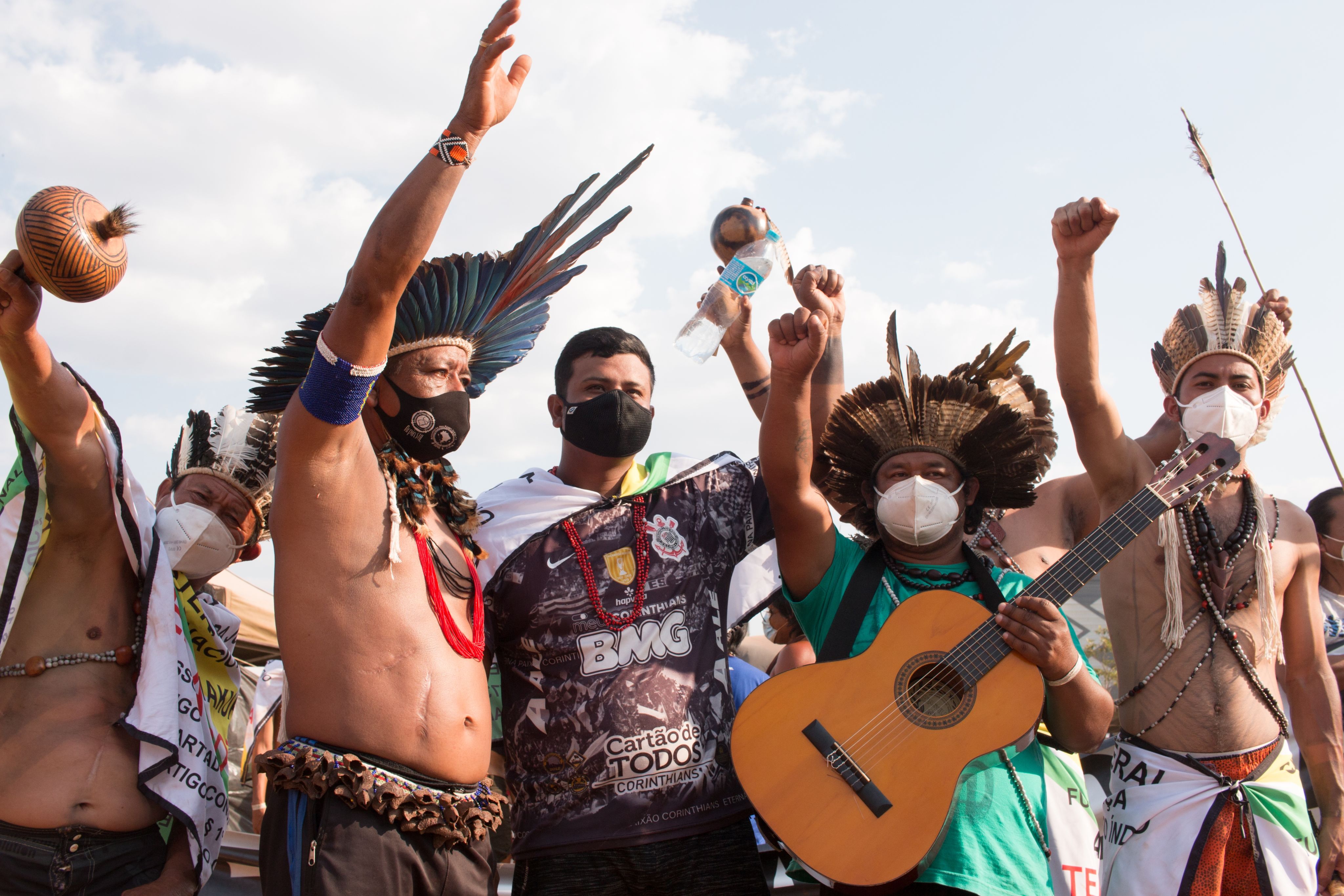Group of Indigenous protesters with raised fists and musical instruments